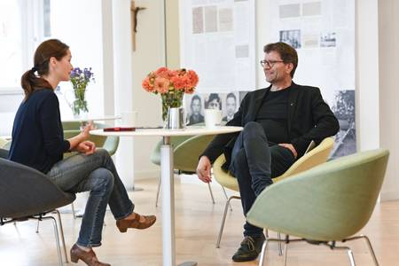 Eine Frau und ein Mann sitzen zusammen am Tisch und unterhalten sich.